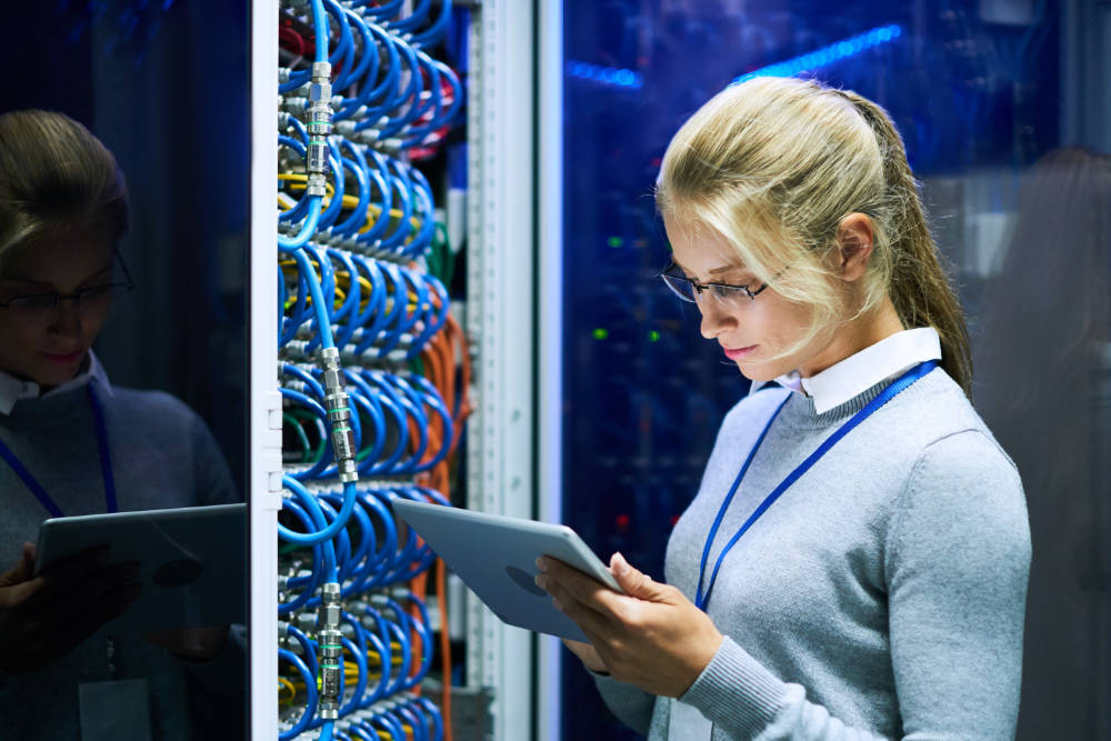 Portrait of young smiling woman checking data on digital tablet while working with supercomputer in research center